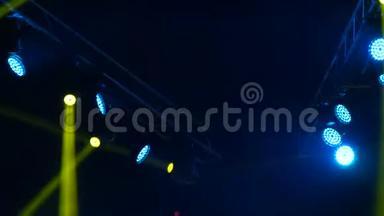 舞台上的蓝色和黄色灯光。 肥皂剧在音乐会上闪闪发光。 发光的舞台灯光在烟雾中闪烁